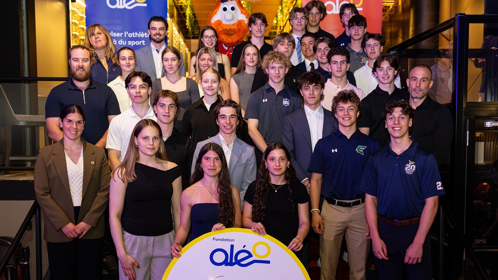 Récipiendaires du Programme de bourses des Canadiens de Montréal 2026 en compagnie de David Savard (à gauche, au milieu), ancien joueur des Canadiens, Alexandra Labelle (à gauche, première rangée), joueuse de la Victoire de Montréal et ancienne boursière de la Fondation Aléo, Martin Lafleur (à droite, au milieu), fils de Guy Lafleur, Patricia Demers (à gauche, en haut), directrice générale de la Fondation Aléo, et de Youppi!